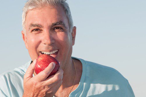 An old men trying to eat an apple