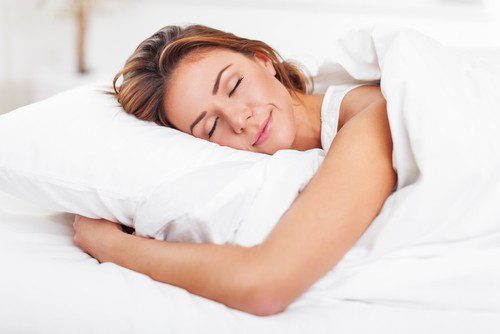 a woman sleeping on a white bed