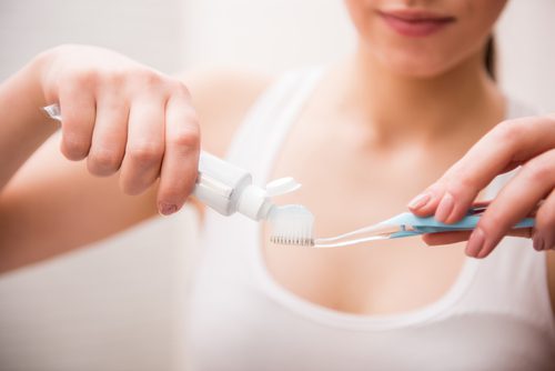 A lady putting a toothpaste on her toothbrush