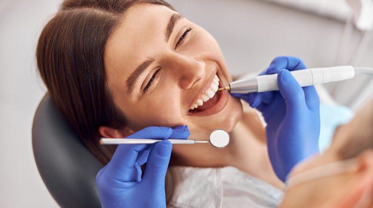 Woman smiling during dental cleaning – Dental Care Tips.