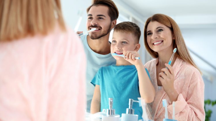 Family brushing their teeth together in the morning, teaching kids how to prevent cavities in kids.